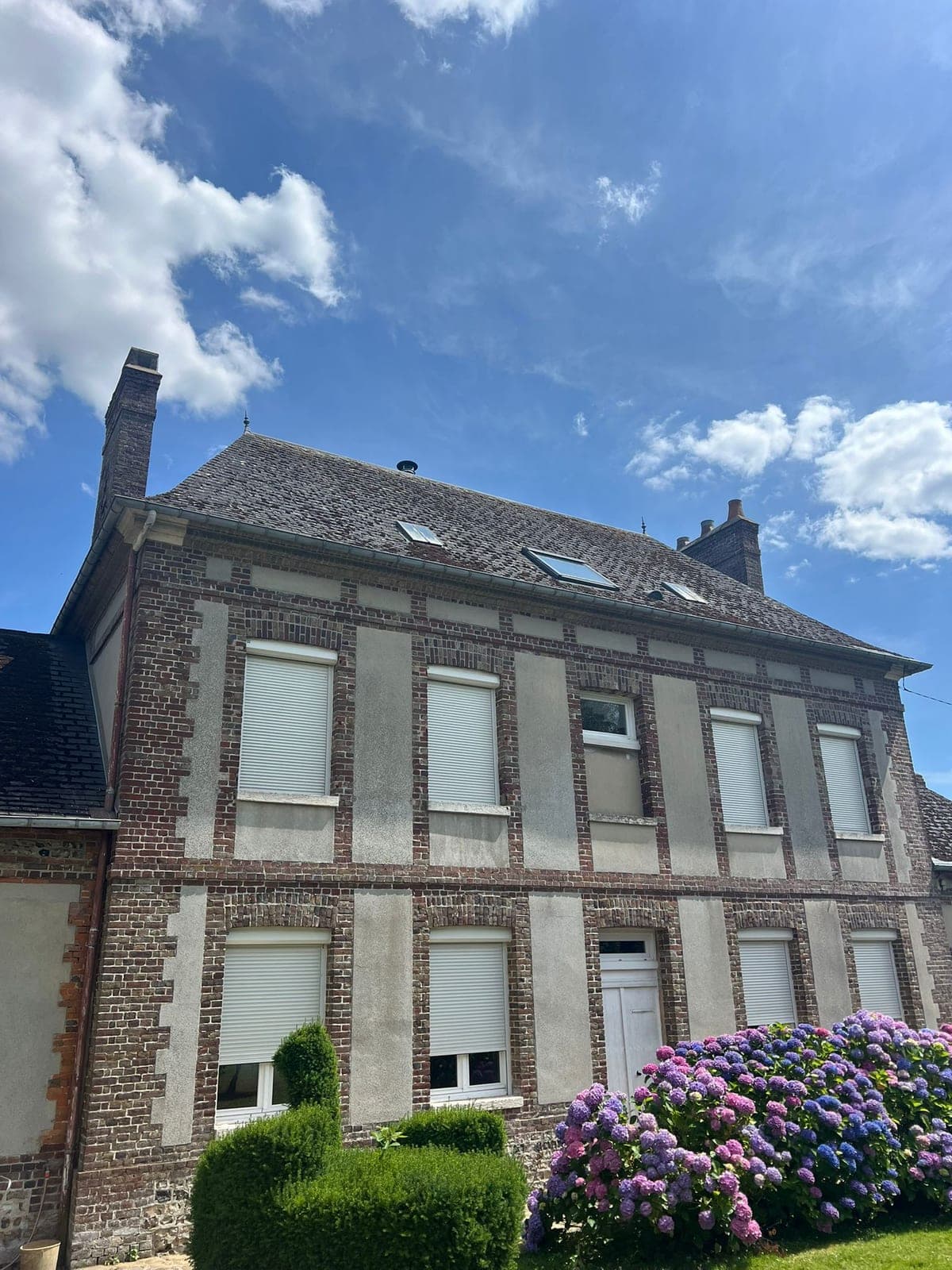 Maison de maître en briques couverte en ardoise naturelle, lucarnes et souches de cheminée.